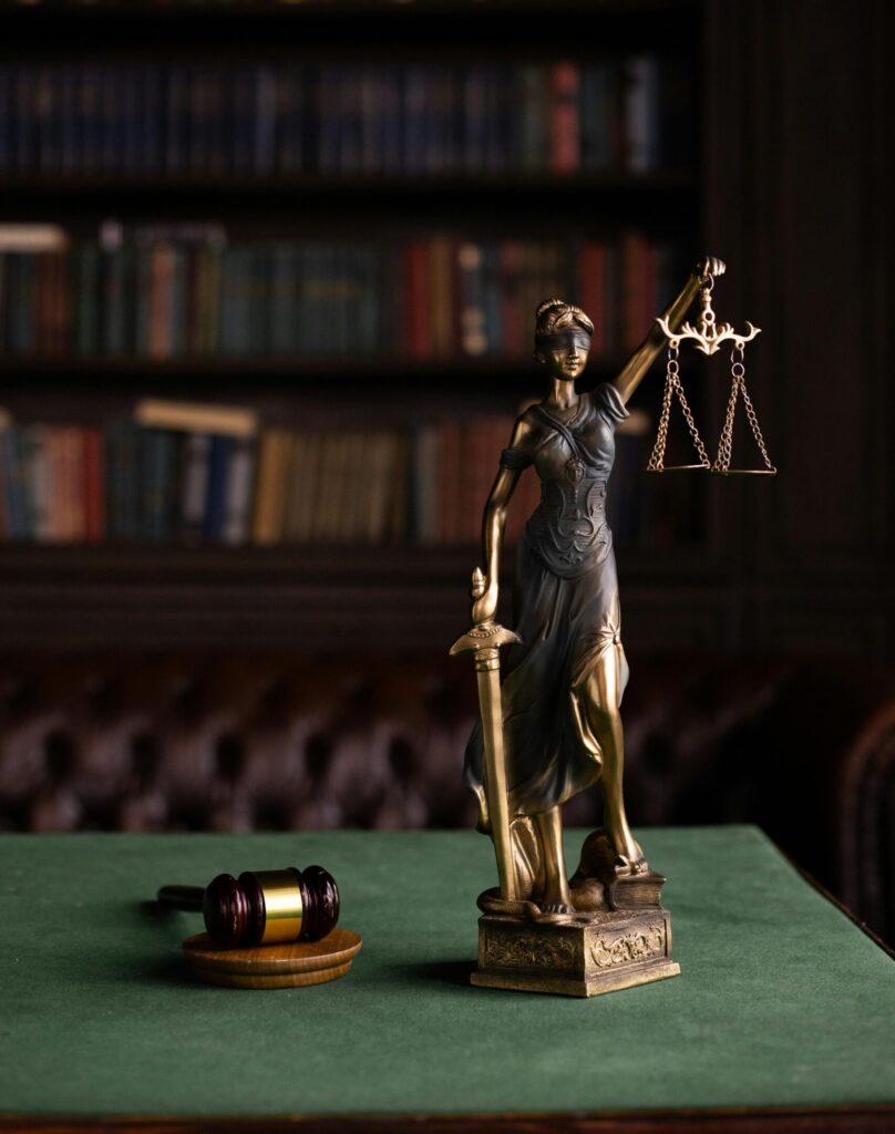 Lady Justice and gavel on a table in a classic law library setting.